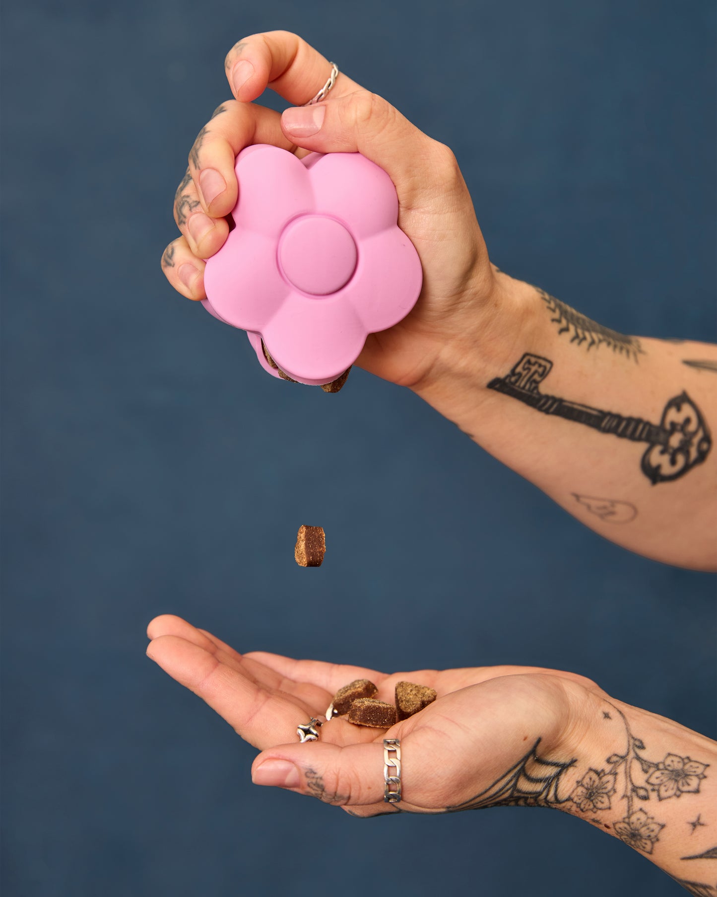Hands holding the pink flower-shaped treat pouch, demonstrating how to dispense treats.