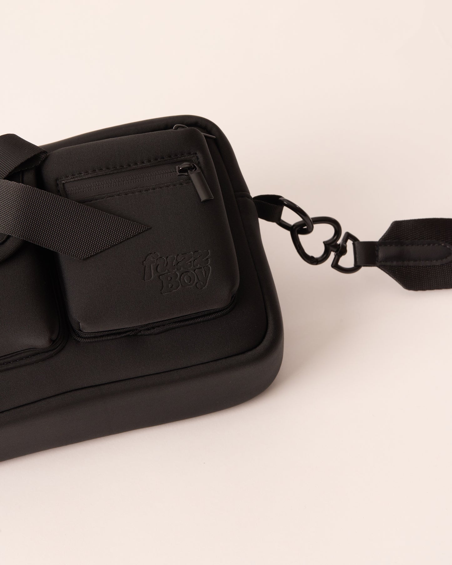 Detail of the black walking bag and the heart-shaped hardware from the detachable strap.