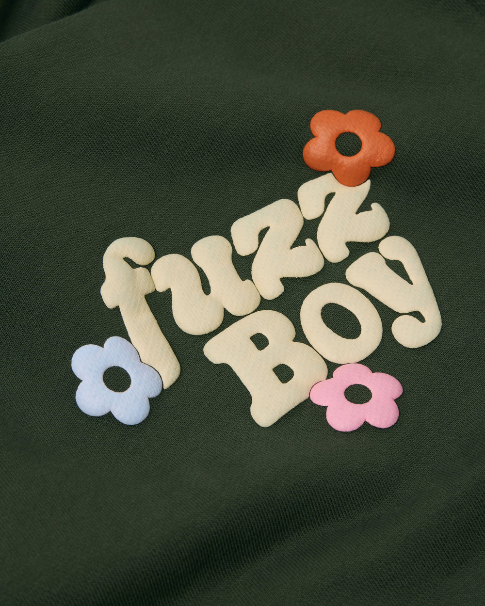Close up of front of the forest green hoodie. Puff printing text reads 'Fuzzboy' with 3 colorful flowers. 