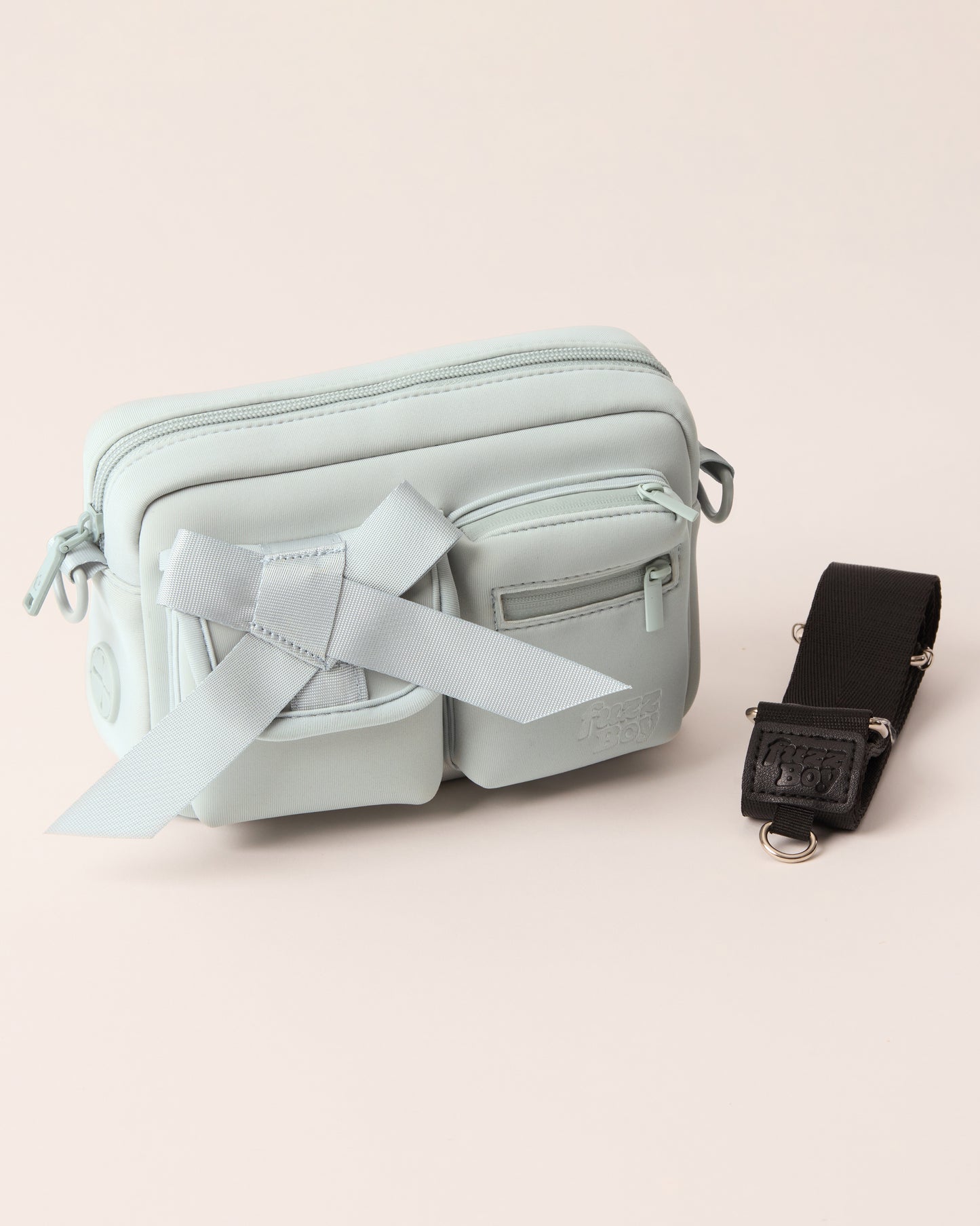 Light blue walking bag with a detachable strap. The bag features two front cargo pockets - on the left is a bow, and on the right are two zipper components.